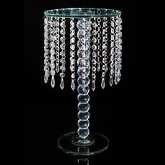 a crystal candle holder with beads hanging from it's sides on a black background