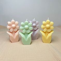 three candles with flowers in them on a table