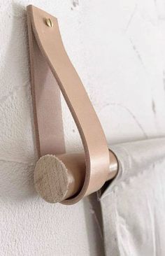 a close up of a hook on a wall with a curtain rod in the corner