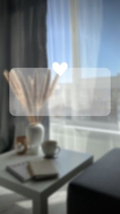 a coffee table with a book and vase on it in front of a large window