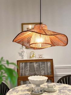 a dining room table with two cups and saucers under a hanging light over it