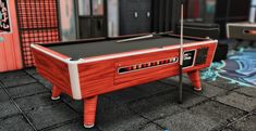 a red pool table sitting on top of a floor next to an arcade game machine