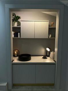 an empty room with shelves and lights on the wall, in front of a potted plant