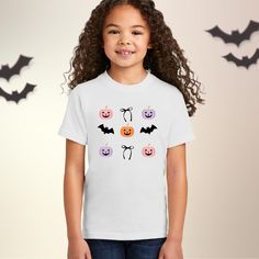 A cozy and casual Kids' T-Shirt featuring a whimsical design of pastel pumpkins, bats and bows. This tee is perfect for children who enjoy a touch of quirky charm in their wardrobe. Ideal for those who appreciate unique, playful fashion. Great for Halloween, fall season, and casual outings. Available in Multiple Sizes: We offer a wide range of sizes to ensure a comfortable fit for all. Please refer to our 2 size charts to find your ideal fit. One is for Toddler sizes, the other for youths. * Unisex, Classic fit * Solid colors are 100% cotton and athletic heather is 90% cotton/10% polyester M E A S U R I N G T I P: Take your favorite tee, lay it flat on a surface and measure from armpit to armpit (width) and top to bottom (length), then compare with our size chart. C A R E I N S T R U C T I Playful Short Sleeve T-shirt For Fall, Playful Short Sleeve Fall T-shirt, Pastel Pumpkins, Playful Fashion, Pumpkin Tshirt, Whimsical Halloween, Whimsical Design, Pumpkin Shirt, Halloween Fall