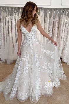 a woman standing in front of a rack of wedding dresses