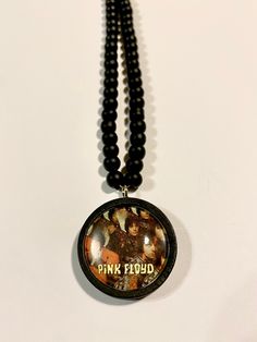 - Handmade Pink Floyd interchangeable pendant with beaded necklace, printed in true vintage style - Wooden beads, stainless steel and clear glass dome setting - 25mm diameter -  Purchase interchangeable pendants separately to wear on your necklace for $10.00 each Each item comes gift wrapped, ready to give, or to spoil yourself! I also make to order, so please let me know your request and I can make your custom order! See my other listings here: https://missswayart.etsy.com Music Accessories, Glass Dome, Glass Domes, Pink Floyd, Necklace Gift, True Vintage, Wooden Beads, Gift Necklace, Vintage Stil