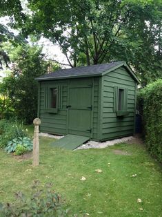 a green shed sitting in the middle of a lush green yard