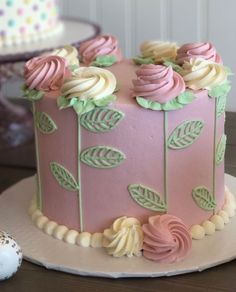 a pink and green cake sitting on top of a table next to a white plate