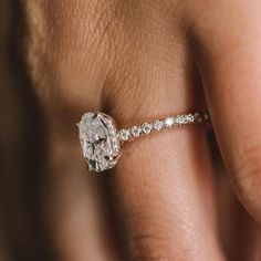 a woman's hand with a diamond ring on her left side and the middle finger