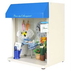 a doll house with flowers and decorations on the shelf next to a blue awning