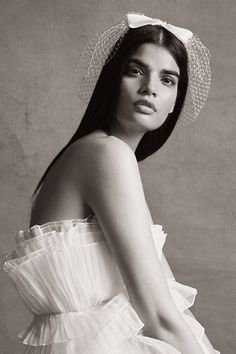 a woman in a white dress and hat poses for the camera with her hands on her hips