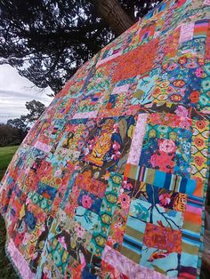 a patchwork quilt is hanging from a tree