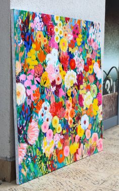 a painting on the side of a building that has flowers painted on it and is next to a wall