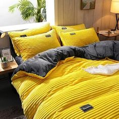 a bed with yellow comforter and pillows in a room next to a night stand