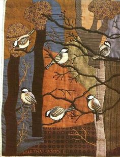 the birds are perched on the tree branches in the patchwork quilted piece, which is hanging from the wall