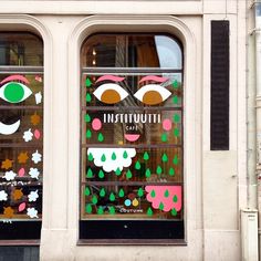 a store front window decorated with paper cut outs and colorful masks on it's windows