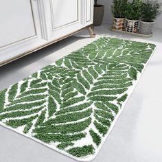 a green and white area rug in the middle of a room with potted plants