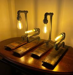 three light bulbs that are sitting on top of a wooden table next to some pipes