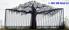 a large metal tree is in front of a white building with black iron bars on it