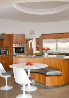 a kitchen with an oval table and white chairs