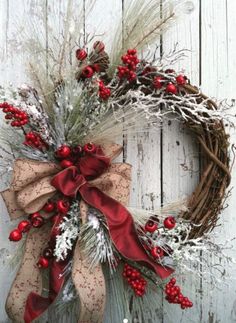 a christmas wreath with red berries and greenery hanging on a white wooden wall next to a door