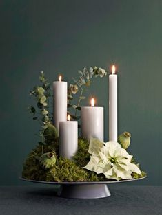 a tray with candles and flowers in it on a table next to a green wall