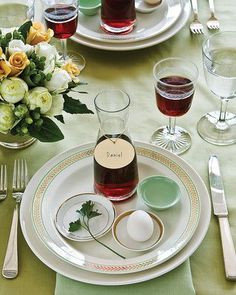 the table is set with dishes, silverware, and flowers in glass vases