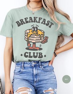 Embrace the joy of mornings with our 'Breakfast Club' tee, where comfort meets whimsy! Crafted from soft, cozy fabric, this shirt features an adorable stack of pancakes, complete with a buttery grin that'll brighten your day. Perfect for lazy brunches or just lounging around, it's a deliciously delightful addition to your wardrobe. Join the club and spread the pancake happiness everywhere you go! Cotton T-shirt With Letter Print For Brunch, Cute Crew Neck Tops For Brunch, Cotton Graphic Print T-shirt For Brunch, Graphic Tee With Letter Print For Brunch, Cotton Graphic Tee For Brunch, Short Sleeve Tops With Funny Print For Brunch, Funny Print Graphic Tee For Brunch, Graphic Print T-shirt For Brunch, Casual Graphic Print T-shirt For Brunch