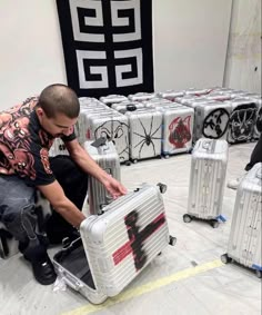 a man sitting on top of a piece of luggage in a room filled with suitcases