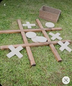 wooden crosses laid out on the grass with bowls and baskets in the backgroud