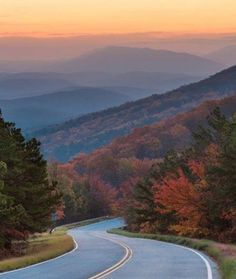 an empty road in the mountains at sunset