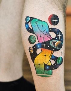 a colorful tattoo on the leg of a man with an elephant and planets around it