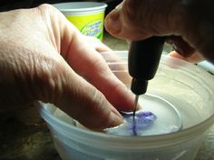 a person is using a drill to fix something in a plastic container with a blue toothbrush