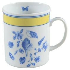 a blue and white coffee cup with yellow trimmings on the bottom, decorated with sea shells