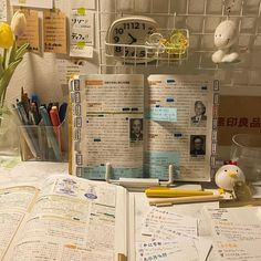 an open book sitting on top of a desk next to a vase with flowers in it