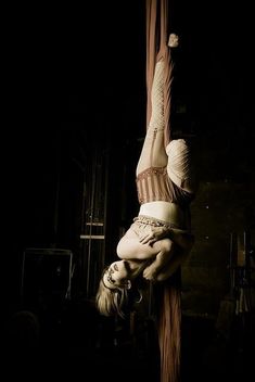 a woman is hanging upside down on a pole with her hands and legs bent over