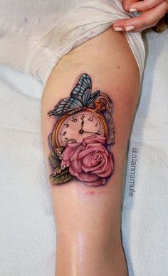 a woman's thigh with a clock and rose tattoo on it