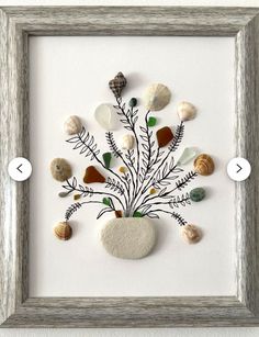 an art piece with shells and sea glass on it, in a white framed frame