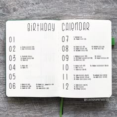 an open birthday calendar on top of a wooden table with a green flower in the middle