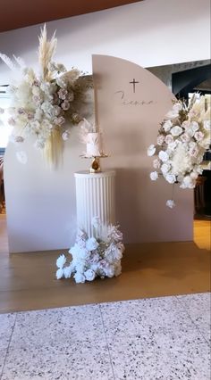 a white vase with flowers and a cross on it sitting in front of a wall