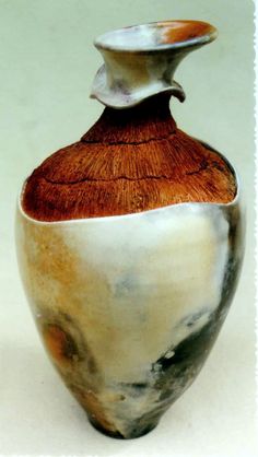 a brown and white vase sitting on top of a table