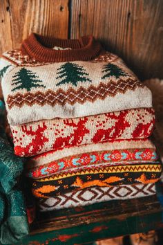 a pile of sweaters sitting on top of a wooden bench