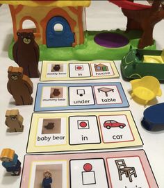 a table with toys and cards on it that include bears, houses, cars, and people