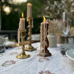 three candles are lit on a table cloth