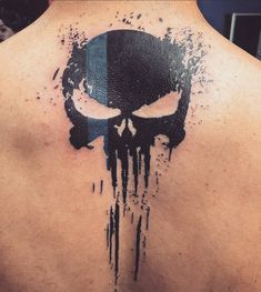 a man's back with a black and blue skull tattoo on it