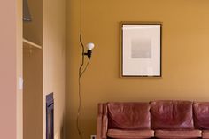 a living room with a brown leather couch and a white framed print on the wall