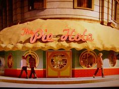 two people walking in front of a store called the pie - hola on broadway