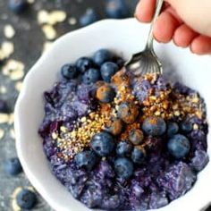 a white bowl filled with blueberries and granola topped with gold flecks