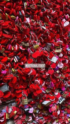 many red padlocks are attached to a wall with a sign that says vernia italy