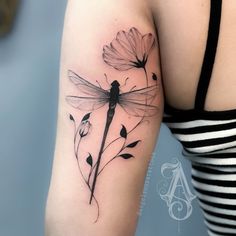 a black and white photo of a woman's arm with a dragonfly tattoo on it